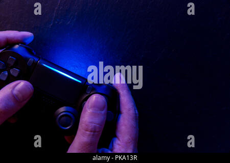 Mann spielt Video Spiel mit Controller in der Nacht mit Beleuchtung Stockfoto