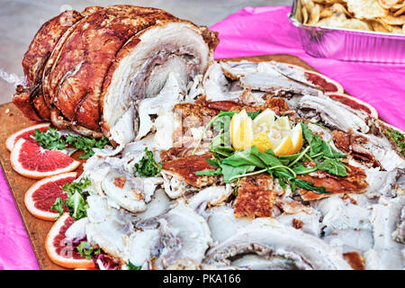 Traditionelle italienische Porchetta mit roten Orangen und Salat auf Holz- fach-selektiven Fokus präsentiert Stockfoto