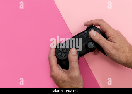 Mann spielt Video Spiel mit Controller auf hellen rosa Hintergrund Stockfoto