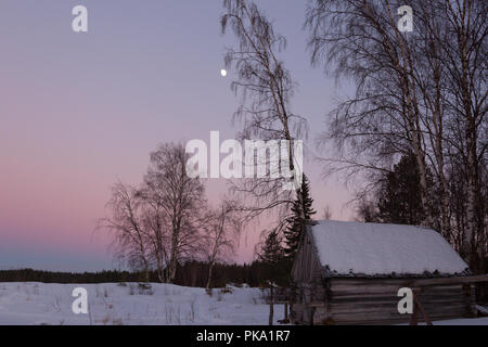 Holz Haus im Dorf, mit Schnee bedeckt und eine Bootsfahrt bei Sonnenuntergang auf einem Winter Stockfoto