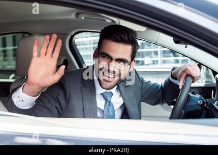 Seitenansicht des fröhlichen Geschäftsmann jemand Gruß während der Fahrt Auto Stockfoto