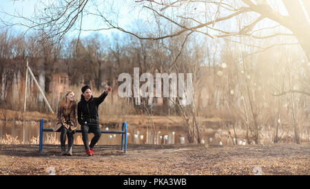 Ein paar junge Menschen im Park getroffen. Liebhaber sitzen auf einer Stockfoto