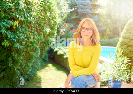 High Angle Shot der schönen Frau mit Pullover und Jeans, während im Garten sitzen und sich entspannen. Stockfoto