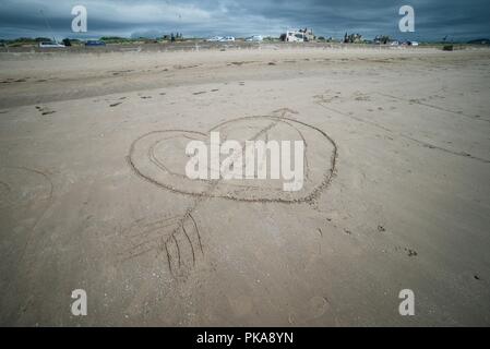 Lovestruck Cupid Herzen in den Sand an einem Sandstrand gezeichnet Stockfoto