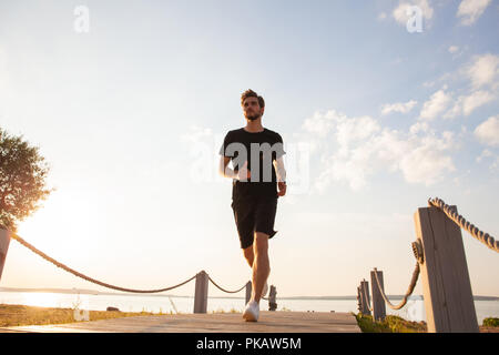 Volle Länge geschossen von gesunden jungen Mann laufen an der Promenade. Männliche Läufer sprintete im Freien Stockfoto