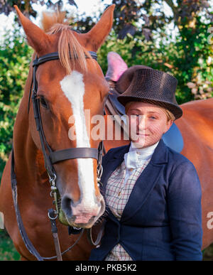 Eine elegante junge Frau mit ihrem Pferd in traditionellen reiten Top Hat und Gesichtsschleier gekleidet Stand Stockfoto