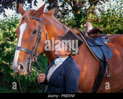 Eine elegante junge Frau mit ihrem Pferd in traditionellen reiten Top Hat und Gesichtsschleier gekleidet Stand Stockfoto