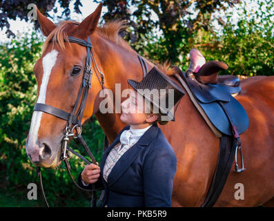 Eine elegante junge Frau mit ihrem Pferd in traditionellen reiten Top Hat und Gesichtsschleier gekleidet Stand Stockfoto