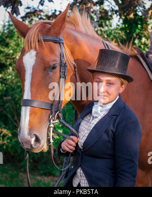 Eine elegante junge Frau mit ihrem Pferd in traditionellen reiten Top Hat und Gesichtsschleier gekleidet Stand Stockfoto