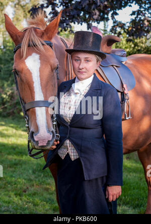 Eine elegante junge Frau mit ihrem Pferd in traditionellen reiten Top Hat und Gesichtsschleier gekleidet Stand Stockfoto