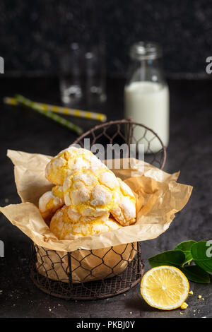 Hausgemachte Zitrone crinkle Plätzchen mit Puderzucker Puderzucker auf Trägerpapier in kleinen Metall, auf dunklem Hintergrund. Vertikale Zusammensetzung Stockfoto
