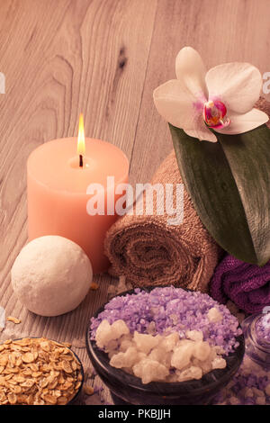 Spa mit Orchidee, Schüssel mit Meersalz, schrubben, Kerze und Handtücher auf Holzbrett Stockfoto