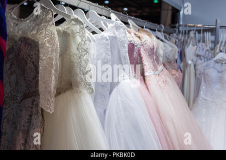 Hochzeits- und Abendkleider hängend an einem Rack im Shop. Stockfoto