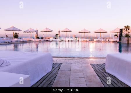 Pastell Sonnenuntergang Licht über Pool und Sonnenliegen Stockfoto