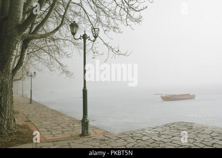 Fußgängerzone Gasse am Ufer des zugefrorenen See Orestiada in misty morning Stockfoto