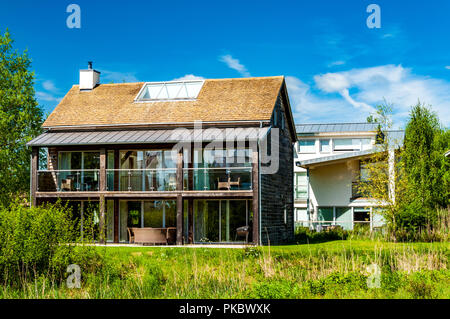 Ein modernes Glas und Holz Haus mit Terrassen und Veranden im Grünland, die Cotswolds, England, Großbritannien Stockfoto