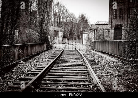 Eisenbahnschienen durch eine verlassene Stadt mit alten Gebäuden Stockfoto