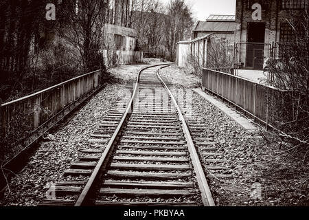 Raiload gehen durch ein Industriegebiet in einer Kurve mit einem sepia Ton Stockfoto