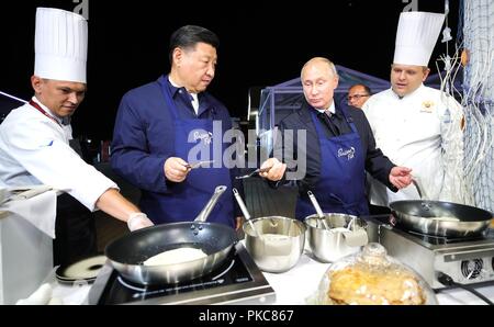 Der russische Präsident Wladimir Putin und der chinesische Präsident Xi Jinping versuchen ihre Hand am Kochen blini gemeinsam an einer Ausstellung während der Eastern Economic Forum im Fernöstlichen Föderalen Universität 11. September, in Wladiwostok, Russland 2018. Stockfoto