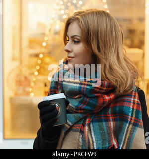 Close-up Portrait von einem süßen Mädchen mit einem Kaffee auf dem Hintergrund der Lichter Stockfoto