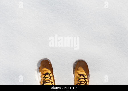 Menschlichen Beinen mit Leder gelb Stiefel im Schnee. Ansicht von oben Stockfoto