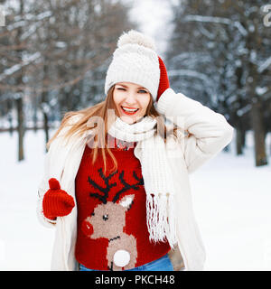 Glückliche junge Mädchen in einem roten Pullover mit Hirsch winks und lächelnd Stockfoto