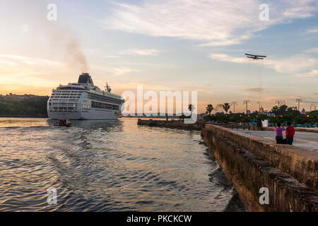 Havanna, Kuba. Juli 2017 04.08. Kreuzfahrtschiff Norwegian Sky macht ihren Weg bis zu Ihrem Dock durch den Piloten Boot begleitet, während eine alte vintage Doppeldecker ov fliegt Stockfoto