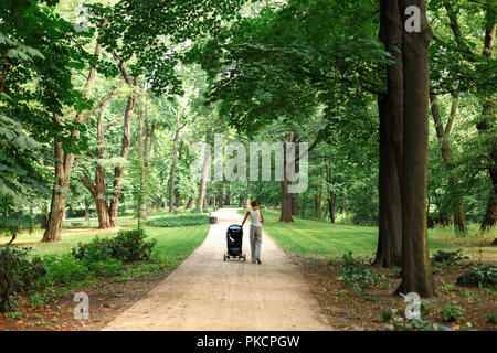 Mom Spaziergänge im Park mit Kinderwagen Stockfoto