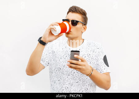 Hübscher Kerl Kaffee trinken und Lesen einer Nachricht auf Ihrem Telefon. Stockfoto