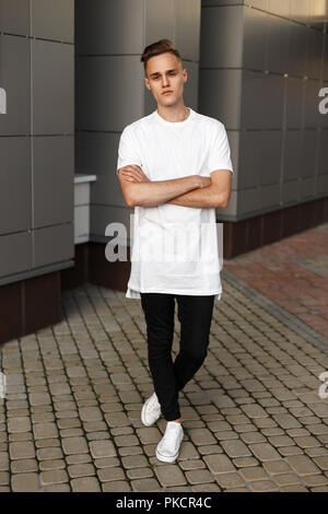Junger hübscher Kerl in der stilvollen Kleidung und Schuhe in der Nähe des modernen Gebäudes posieren. Stockfoto