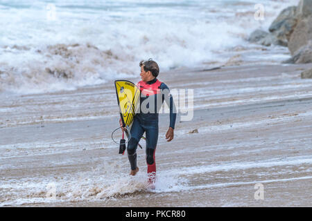 Ein junger Surfer zu Fuß aus dem Meer auf den Fistral Beach in Newquay Cornwall. Stockfoto