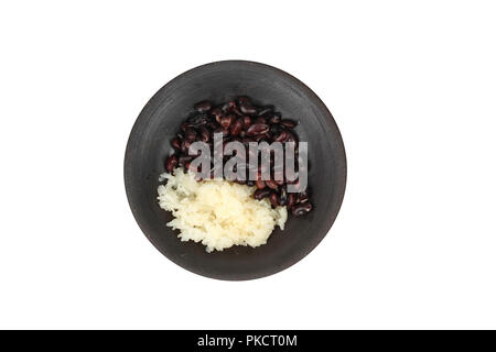 Isolted thailändisches Dessert. Schwarze Bohne und klebriger Reis in süßen Kokoscreme überstieg Kokosmilch in schwarze Platte auf Holz. Stockfoto