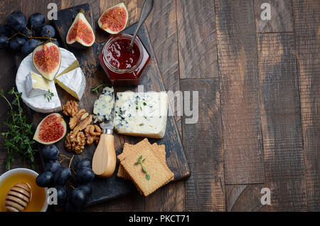 Käseplatte mit Trauben, Feigen, Cracker, Honig, Pflaumen Gelee, Thymian und Muttern, selektive konzentrieren. Stockfoto
