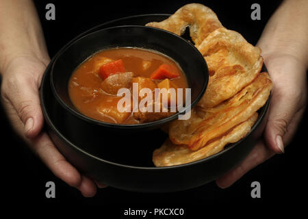 Fertig serviert von Roti, indisches Essen wie frittierte Mehl, mit Japanischen Gelb auf schwarzem Hintergrund Curry. Stockfoto