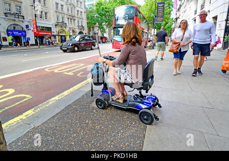 Frau auf einem Mobilität scooter an einer Bushaltestelle in Central London, England, UK. Stockfoto