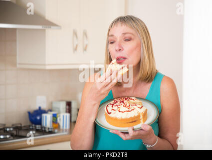 Frau essen eine Creme Biskuitteig Stockfoto
