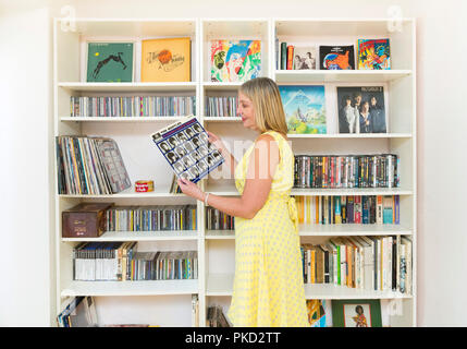 Frau Durchsuchen einer Musik Sammlung von Schallplatten und Compact Discs Stockfoto