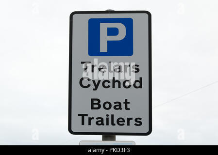 Die walisische Sprache Parkplätze für Bootsanhänger (Trelars Cychod) Zeichen mit schwarzem Text auf weißem Hintergrund mit blauen P Parkplatz Symbol gegen klar weiß Himmel Stockfoto