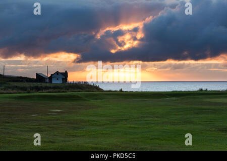 Dramatischer Sonnenuntergang durch dunkle Wolken über der Nord Antrim Coast, Portstewart, N. Irland zu brechen. Stockfoto