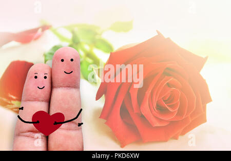 Zwei Finger mit Herz. Ein glückliches Paar in der Liebe mit gemalten Smiley halten roten Herzen Stockfoto