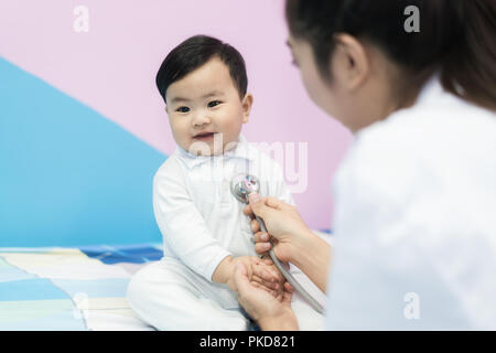 Asiatische Arzt Frau Prüfung eines kleinen Jungen durch Stethoskop im Krankenhaus. Medizin und Gesundheit Konzept. Stockfoto