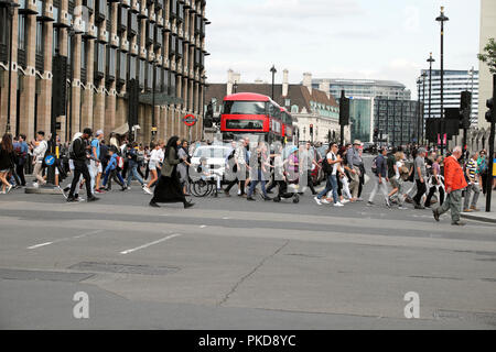 Passanten und Touristen, überqueren Sie die Straße an der Bridge Street Ampel Zebrastreifen außerhalb der Häuser des Parlaments von Westminster London UK Stockfoto