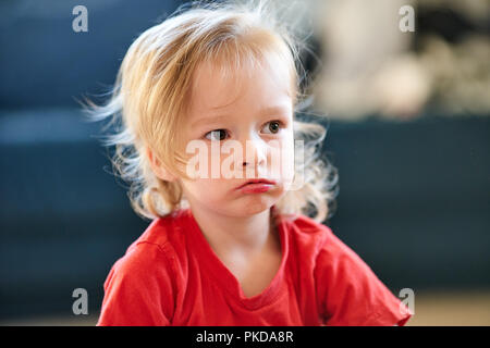 Schöne blonde Mädchen mit roten T-Shirt ist Siiting wütend traurig Stockfoto