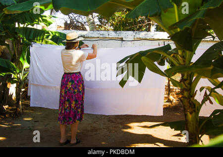 Frau hängende Blätter, die auf einer Wäscheleine im Freien Stockfoto