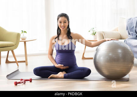 Fröhliche schwangere Frau zu Hause trainieren Stockfoto
