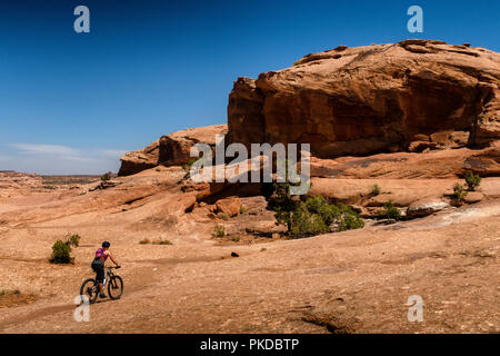 Eine Frau reitet ein Mountainbike auf der weltberühmten Slickrock Trail in Moab, Utah, USA. Stockfoto