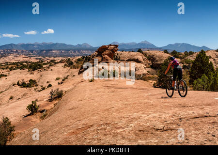 Eine Frau reitet ein Mountainbike auf der weltberühmten Slickrock Trail in Moab, Utah, USA. Stockfoto