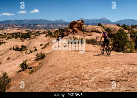 Eine Frau reitet ein Mountainbike auf der weltberühmten Slickrock Trail in Moab, Utah, USA. Stockfoto