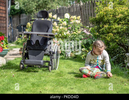 Ein behindertes Kind in eine Pause vom Sitzen in Ihrem Rollstuhl ihre natürliche Umgebung zu erkunden Stockfoto