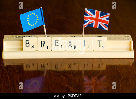 Scrabble Buchstaben Rechtschreibung Brexit in Scrabble Fach mit dem britischen Union Jack und EU-Flaggen auf dunklem Mahagoni Hintergrund Stockfoto